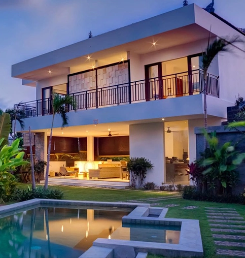 A large white house with a pool in front of it.