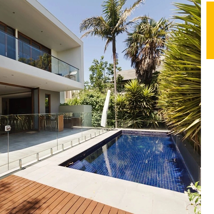 A pool in the middle of a house with palm trees.