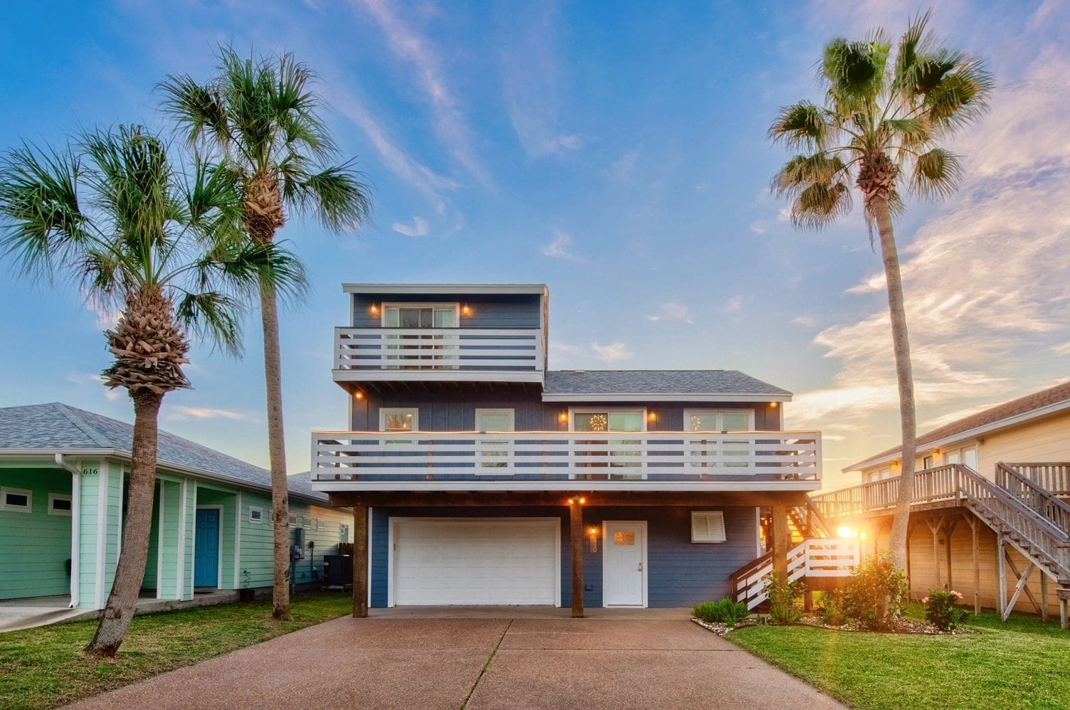 A house with a garage and palm trees in the background.