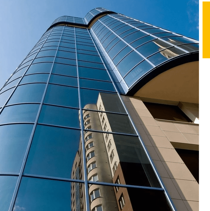 A tall building with many windows and a yellow sky